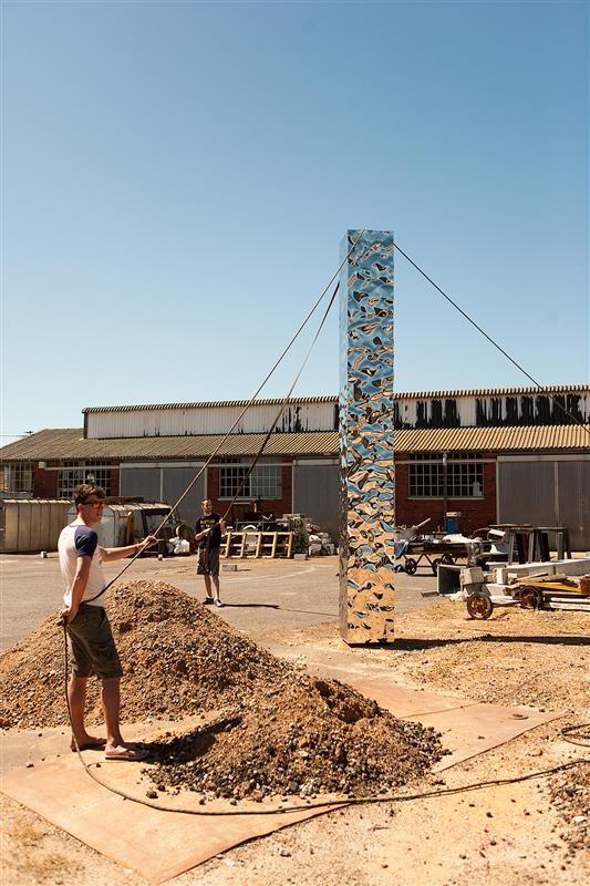 Close-up of the sculptural base of a large mirrored stainless-steel column.